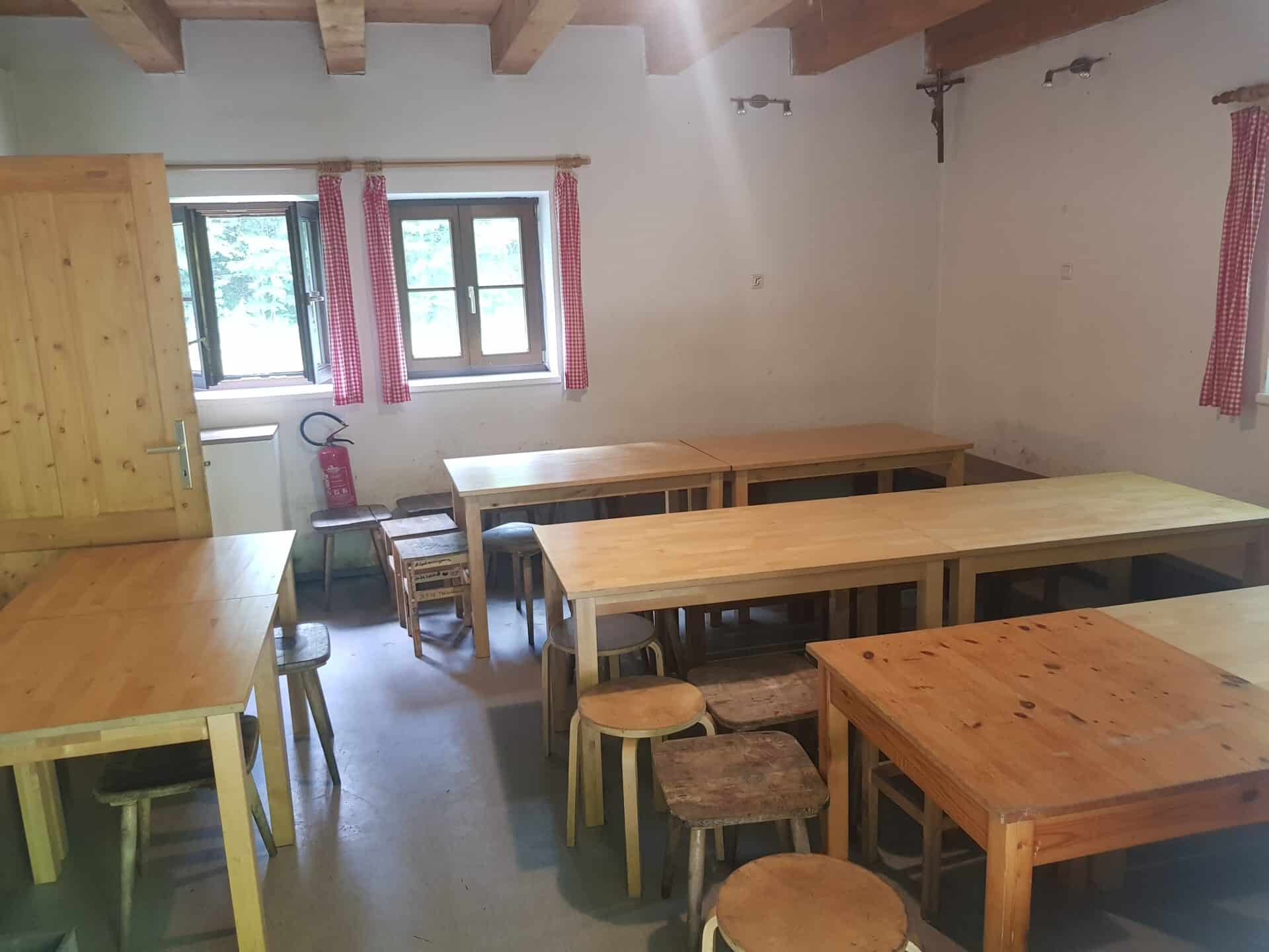 Am Foto ist der Aufenthaltsraum zu sehen. Man sieht acht Tische sowie Hocker und Bänke. Die Tische sind als Doppeltische nageordnet. Pro Doppeltisch können circa 10 Personen sitzen. Man sieht also circa 40 Sitzplätze. Außerdem sind 3 Fenster und ein Feuerlöscher erkennbar.